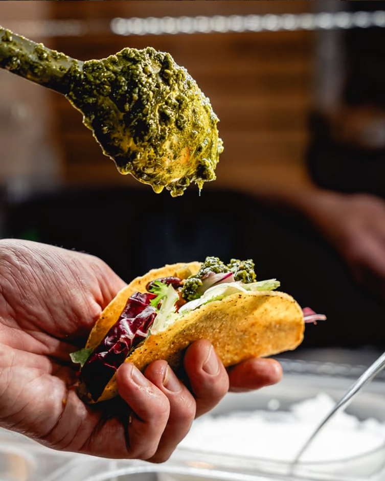 Ruka drží taco s bylinkovou omáčkou